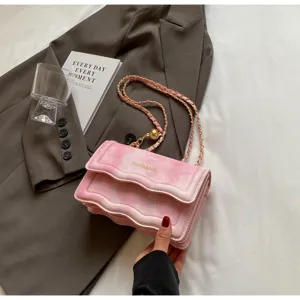 Detail shot of pink wavy quilted chain shoulder bag with elegant gold strap and luxury fashion style.