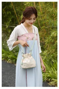 Detailed view of the embroidered bucket bag in a natural bamboo forest setting.