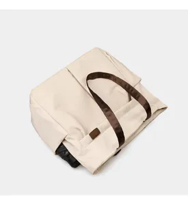 Detail view of casual beige tote shoulder bag with brown straps and side pocket for daily commute.