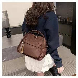 Detail view of a brown minimalist commuter shoulder bag and backpack in an indoor setting.
