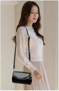 Detailed view of women black PU leather crossbody bag with gold hardware and flap design.