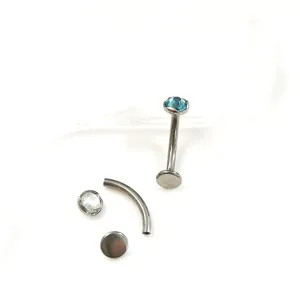 Titan Piercing Schmuck mit Labret Stecker, gebogener Hantel und glänzenden Kristallstein Aufsätzen.