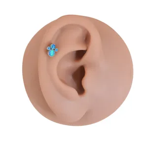Detailed view of blue opal cat paw cartilage piercing stud on ear model, stylish body jewelry.