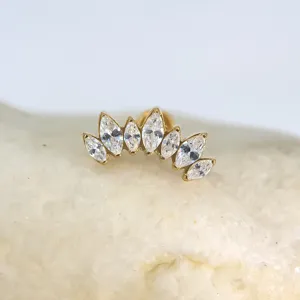 Detailweergave van gouden lichaampiercing met schitterende markies zirconiasteentjes erop.