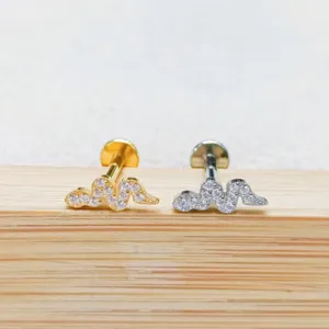 Primo piano dettaglio di piercing labret ondulato con zirconi in oro e argento titanio.