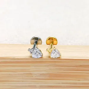 Detailaufnahme von Titan und Gold Piercing Ohrringen mit funkelnden Zirkonsteinen.