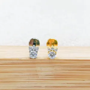 Nahaufnahme von Titan- und 18k Gold-Piercing-Stiften mit funkelnden Zirkonias, Detailansicht.