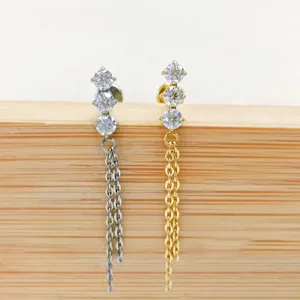 Detail shot of titanium cartilage piercing studs featuring triple zirconia and hanging chains.