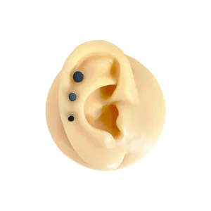 Close-up detail of titanium flat top body piercing stud accessory, smooth round disc design.