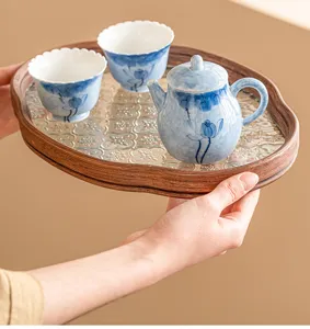 Detail view of hand-painted blue lotus ceramic tea set with wooden tray, elegant design.