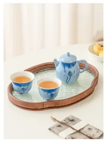 Hand-painted blue lotus ceramic teapot and two cups set detail on wooden glass tea tray.