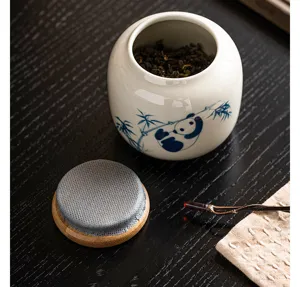 Détail du pot à thé en céramique avec motif panda peint à la main et couvercle en bois.