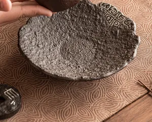 Nahaufnahme Detail eines dunklen, rauen Keramik Teekannenhalters, rustikaler Teeteller.