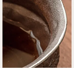 Primo piano dettagliato del bordo della ciotola da tè in ceramica ruvida con finitura argentata.