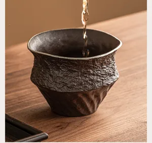 Dettaglio tazza da tè in ceramica grossolana, accessorio retrò con bordo argentato.