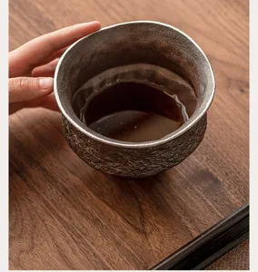 Primo piano dettagliato di una tazza da tè in ceramica rustica con bordo argentato.