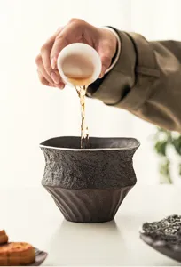 Dettaglio della ciotola lavatè in ceramica grezza, elegante contenitore d'acqua da tè scuro.