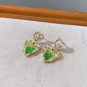 Exquisite green crystal and pearl heart earrings detail shot, elegant fashion jewelry accessory.