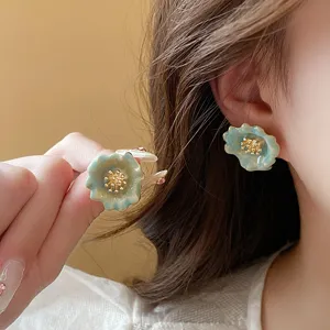 Close-up detail shot of gradient green flower earrings with gold stamen, elegant and fresh.