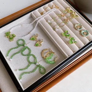 Detailed view of trendy green crystal pearl necklace and bow flower heart earrings jewelry set.