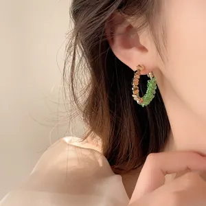 Detail shot of trendy gold and green crystal split hoop earrings, chic jewelry design.