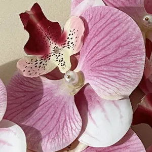 Nahaufnahme Detailansicht der rosa und weißen Orchideen-Haarspange mit Perlenakzent.