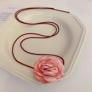 Collier fleur en tissu rose avec cordon rouge fonce, design elegant pour vacances et quotidien.