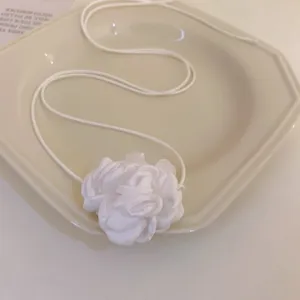 Gros plan d'un collier ras du cou chic en tissu floral blanc, accessoire de bijoux élégant.