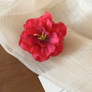 Primer plano de la pinza de pelo de flor de tela roja romántica con pétalos delicados.