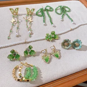 Detail view of green crystal bow butterfly heart flower earrings and pearl jewelry set.