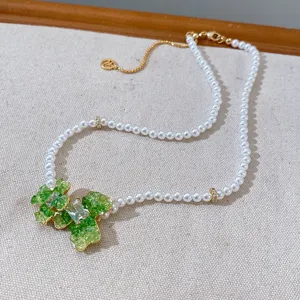 Elegant pearl necklace featuring green crystal flower pendant and gold-tone chain details.