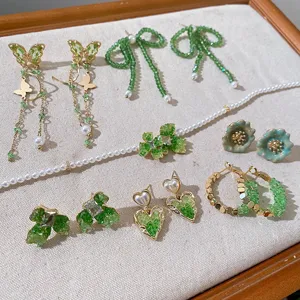 Detailed view of trendy green crystal earrings and pearl jewelry set with bow and butterfly.