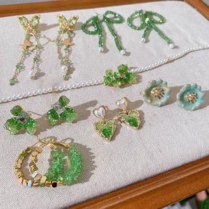 Detailed view of exquisite green crystal butterfly flower bow earrings and pearl necklace set.