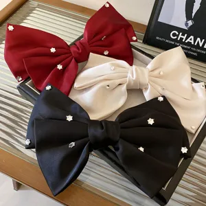 Detailed shot of French rhinestone bow hair clips, elegant satin fabric with sparkling crystals.