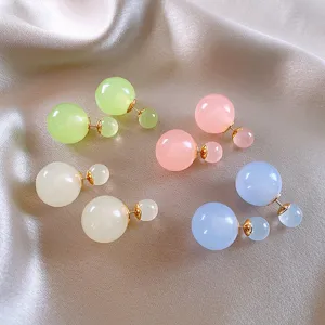 Primo piano dettagliato di orecchini a sfera in vetro colorato con perni dorati.