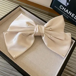 Elegant beige satin bow hair clip with sparkling rhinestones, chic spring clip design accessory.