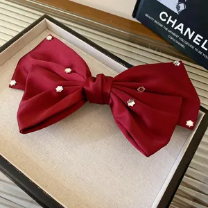 Detailed close-up of wine red satin bow hair clip featuring sparkling crystal rhinestone studs.