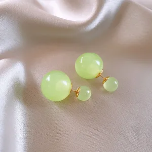 Primo piano dettagliato degli orecchini a doppia sfera in vetro con perno dorato, chic.