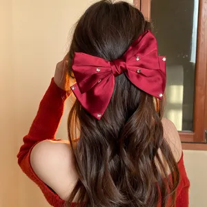 Red satin rhinestone bow hair clip detail, elegant oversized hair accessory for women.