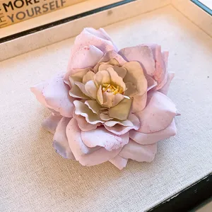Close-up detail of a soft fabric rose hair clip with pink petals placed in a neat display tray.