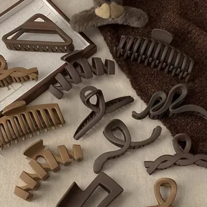 Set di mollette per capelli geometriche opache marroni, vista dettaglio stile minimalista.