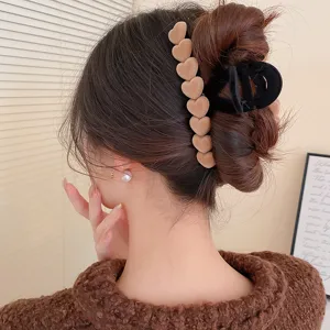 Dettagli del fermaglio per capelli a cuore in velluto marrone e della pinza geometrica nera.