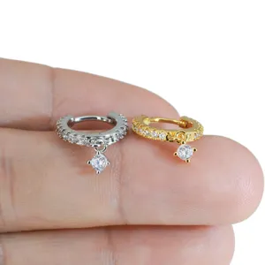 Detailaufnahme von kleinen runden Zirkonia Huggie Creolen Ohrringen in Gold und Silber Tönen.