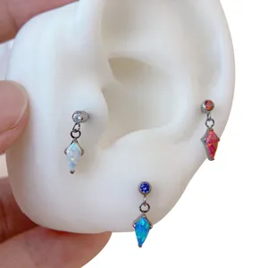 Close-up detail of titanium piercing jewelry featuring colorful opal kite stone pendants.
