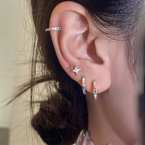 Primo piano dettagliato di bellissimi manicotti per orecchie in zircone colorato e orecchini.