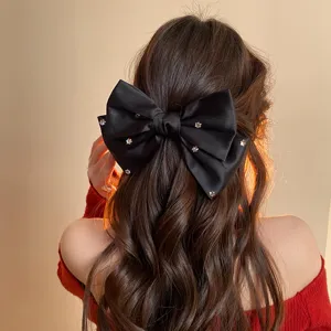 French minimalist black satin bow hair clip with sparkling rhinestones, elegant detail.