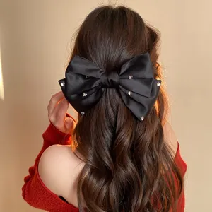 Detailed view of the black satin rhinestone bow hair clip, highlighting crystal details.