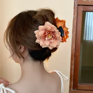 Close up of a large fabric rose hair claw clip showcasing the detailed petals and updo style.
