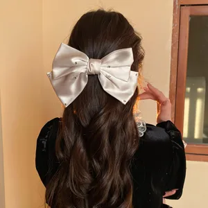 Close-up detail of the elegant satin bow hair clip showcasing sparkling rhinestones.