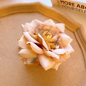 Close-up detail of a vintage dried rose flower hair claw clip, featuring gradient fabric petals.